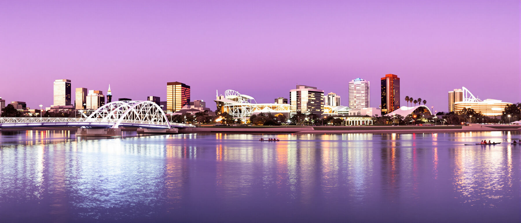 Adelaide city skyline and the footbridge over the River Torrens at dusk with rowers on the water
