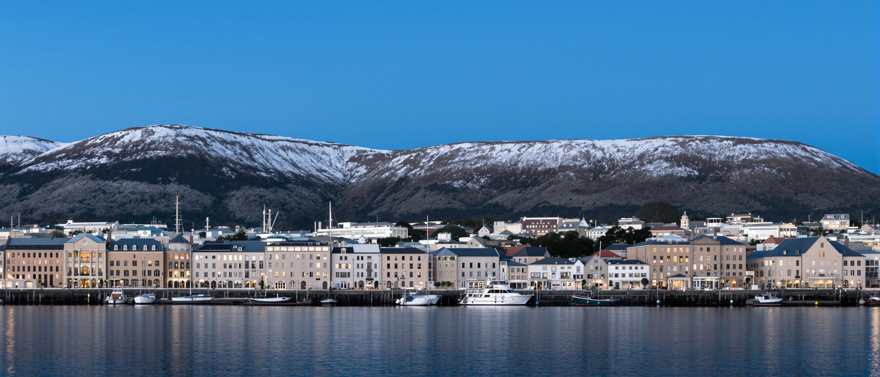Hobart waterfront at dusk with sandstone warehouses, fishing boats and the mountain behind the city